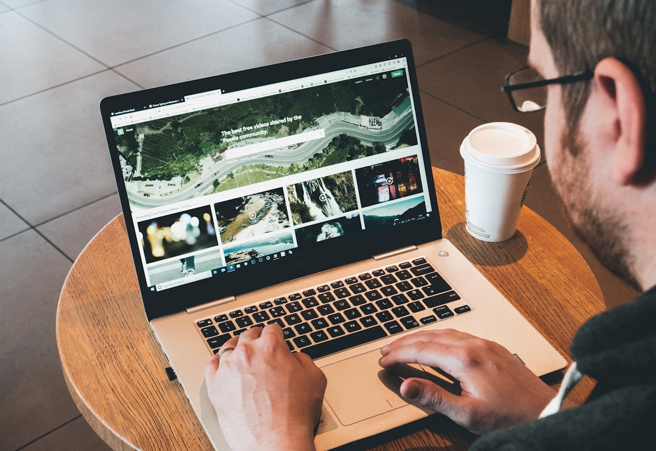 about-01 Man working on a laptop in a modern workspace with a coffee cup nearby, showcasing online activity.